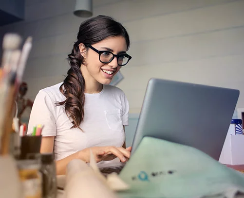 Young woman working at laptop in modern office, engaged in creative digital marketing tasks.